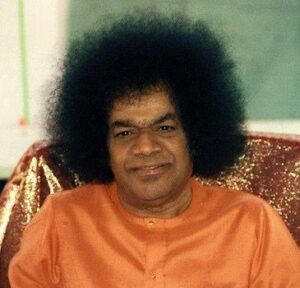 sri sathya sai baba Person with large curly hair, orange attire.
