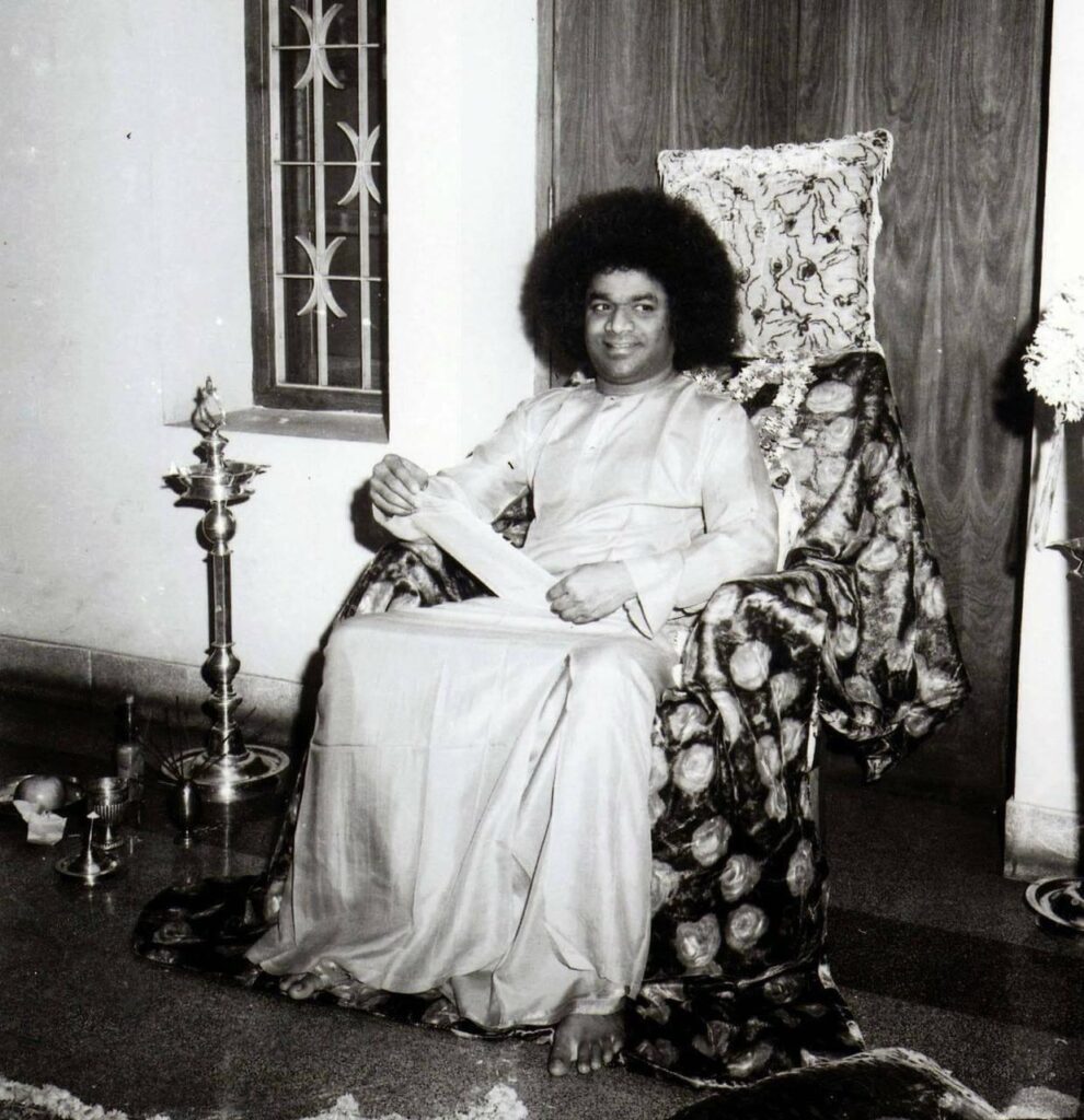 shri sathya sai baba seated in traditional attire.