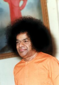 shri sathya sai baba in orange attire with afro photo