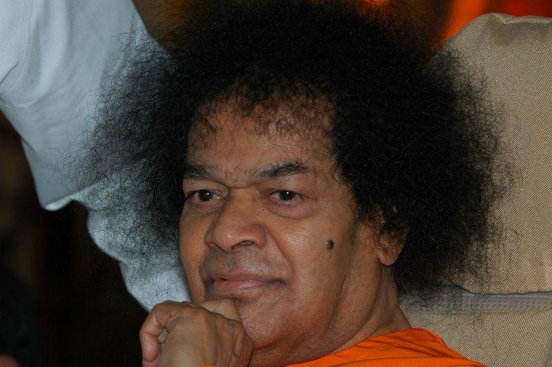 shri sathya sai baba in orange robe resting chin on hand