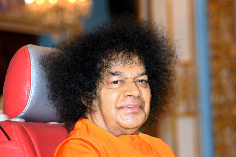 Sathya Sai Baba in red chair picture.