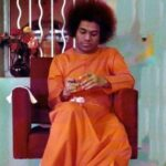 Sathya Sai Baba looking at his hands.