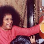 Smiling Sathya Sai Baba holding a mandolin