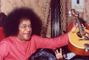 Shri Sathya Sai Baba holding musical instrument