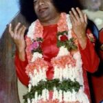 Sathya Sai Baba raising hands with garland