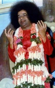 Sathya Sai Baba raising hands with garland