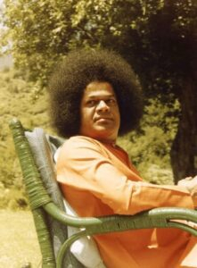 Sathya Sai Baba seated in nature photo.