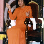 Sathya Sai Baba gesturing from his throne.