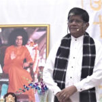 Spiritual speaker before Bhagwan Shri Sathya Sai portrait