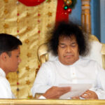 Sathya Sai Baba holding a white paper.
