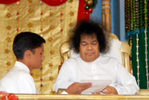 Sathya Sai Baba holding a white paper.