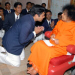 Shri Sathya Sai Baba blessing kneeling devotee