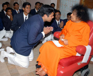 Shri Sathya Sai Baba blessing kneeling devotee