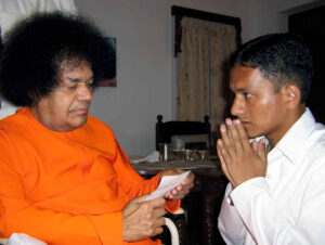 Shri Sathya Sai Baba blessing a praying devotee