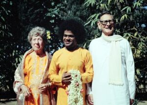 Sathya Sai Baba standing with devotees outdoors.