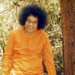 Sri Sathya Sai Baba smiling amidst peaceful forest nature