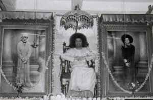 Sathya Sai Baba seated between two portraits.