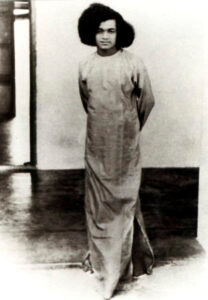 Young Sathya Sai Baba standing looking forward.