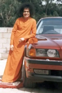 Sri Sathya Sai Baba standing beside car with smile