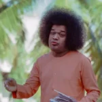 Sathya Sai Baba holding letters outdoors