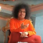Sri Sathya Sai Baba giving divine blessings seated