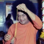Sri Sathya Sai Baba holding sacred prayer garland