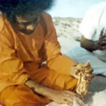 Sathya Sai Baba holding a Krishna statue.