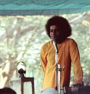 Sri Sathya Sai Baba delivering spiritual discourse outdoors