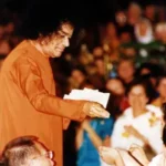 Sri Sathya Sai Baba giving vibhuti to devotee