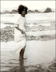 Young Sri Sathya Sai Baba walking through sacred river
