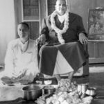Swami Sivananda blessing devotee beside sacred food offering