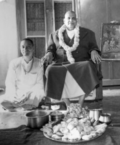 Swami Sivananda blessing devotee beside sacred food offering