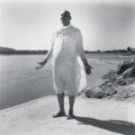 Swami Sivananda standing peacefully beside sacred riverside