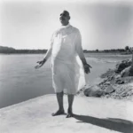 Swami Sivananda standing peacefully beside sacred riverside