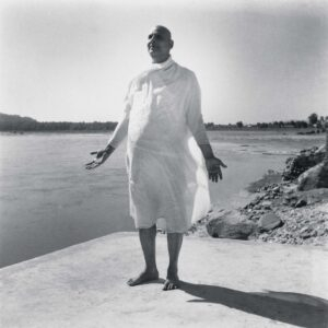 Swami Sivananda standing peacefully beside sacred riverside