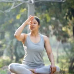Woman practicing Nadi Shodhana Pranayama in a peaceful outdoor setting