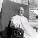 Swami Sivananda seated peacefully on wooden chair