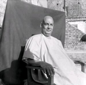 Swami Sivananda seated peacefully on wooden chair