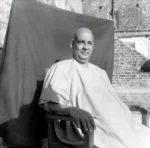 Swami Sivananda seated peacefully on wooden chair