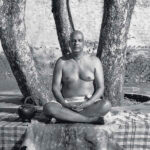 Swami Sivananda meditating beneath a tree in lotus pose