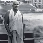 Swami Krishnananda standing peacefully with walking stick