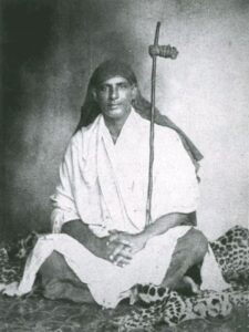 Young Swami Sivananda meditating with staff