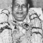 Swami Sivananda wearing multiple flower garlands during ceremony