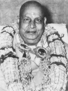 Swami Sivananda wearing multiple flower garlands during ceremony