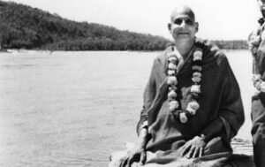 Swami Sivananda beside river sharing timeless spiritual wisdom
