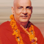 Swami Sivananda wearing flower garlands smiling peacefully