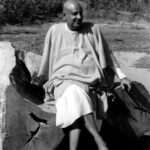 Swami Sivananda contemplating Vedanta beside peaceful nature
