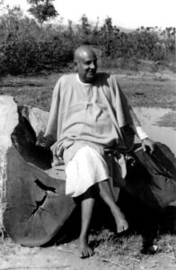 Swami Sivananda contemplating Vedanta beside peaceful nature