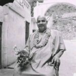 Swami Sivananda holding flowers with peaceful smile