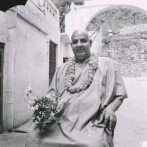 Swami Sivananda holding flowers with peaceful smile